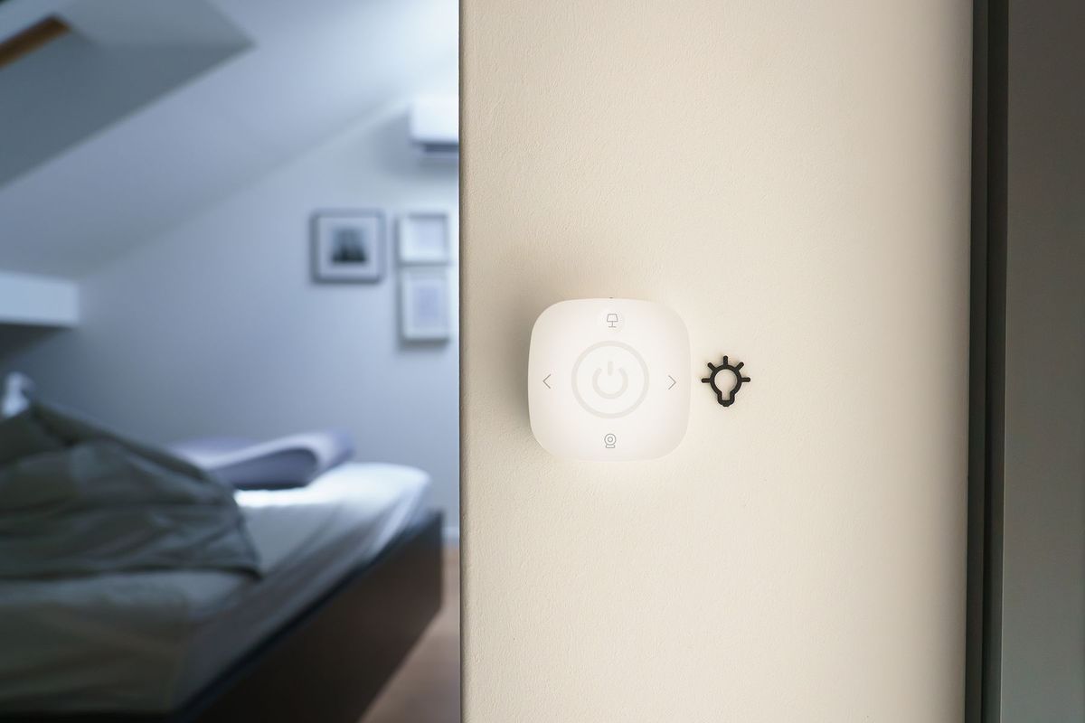 Mano ajustando un panel de control domótico en la pared