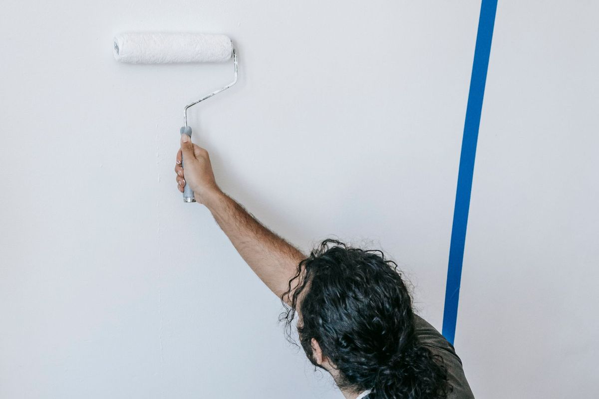 Pintor pasando el rodillo en una pared blanca de un piso