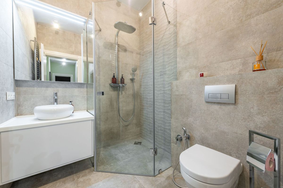 Baño reformado con plato de ducha, mampara y azulejo claro