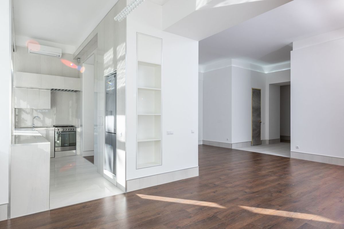 Salón de un piso reformado con suelo de madera y paredes blancas